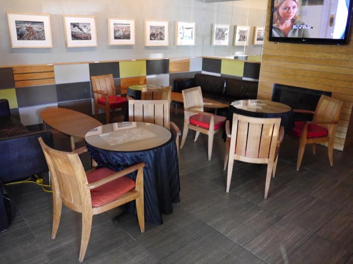 Café tables beneath a long line of framed prints