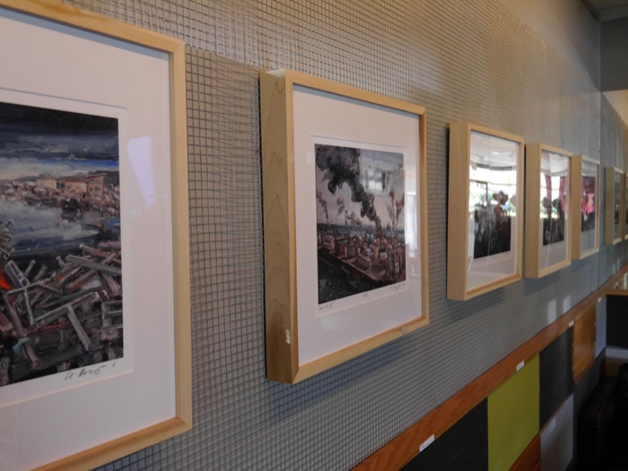 Framed paintings running down the wall, seen at an angle
