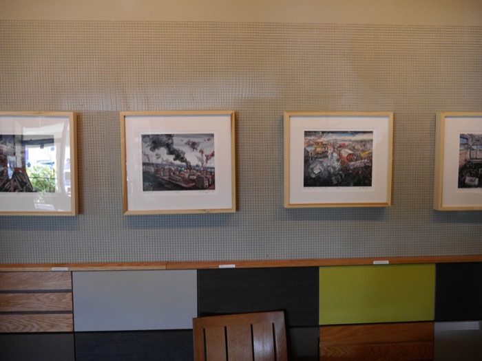 A row of framed paintings along the wall above the booths