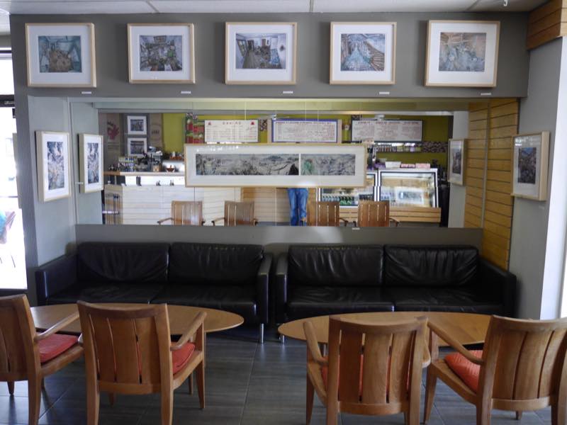 A row of framed paintings above the leather sofa and the bar