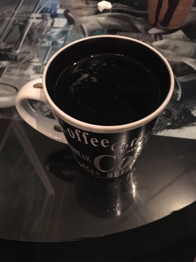 A mug of black coffee on a glass-topped table