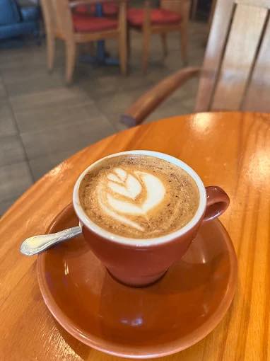 A cortado with latte art on a wooden table