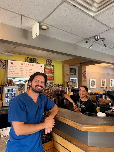 A smiling regular leaning on the counter while the barista smiles behind it
