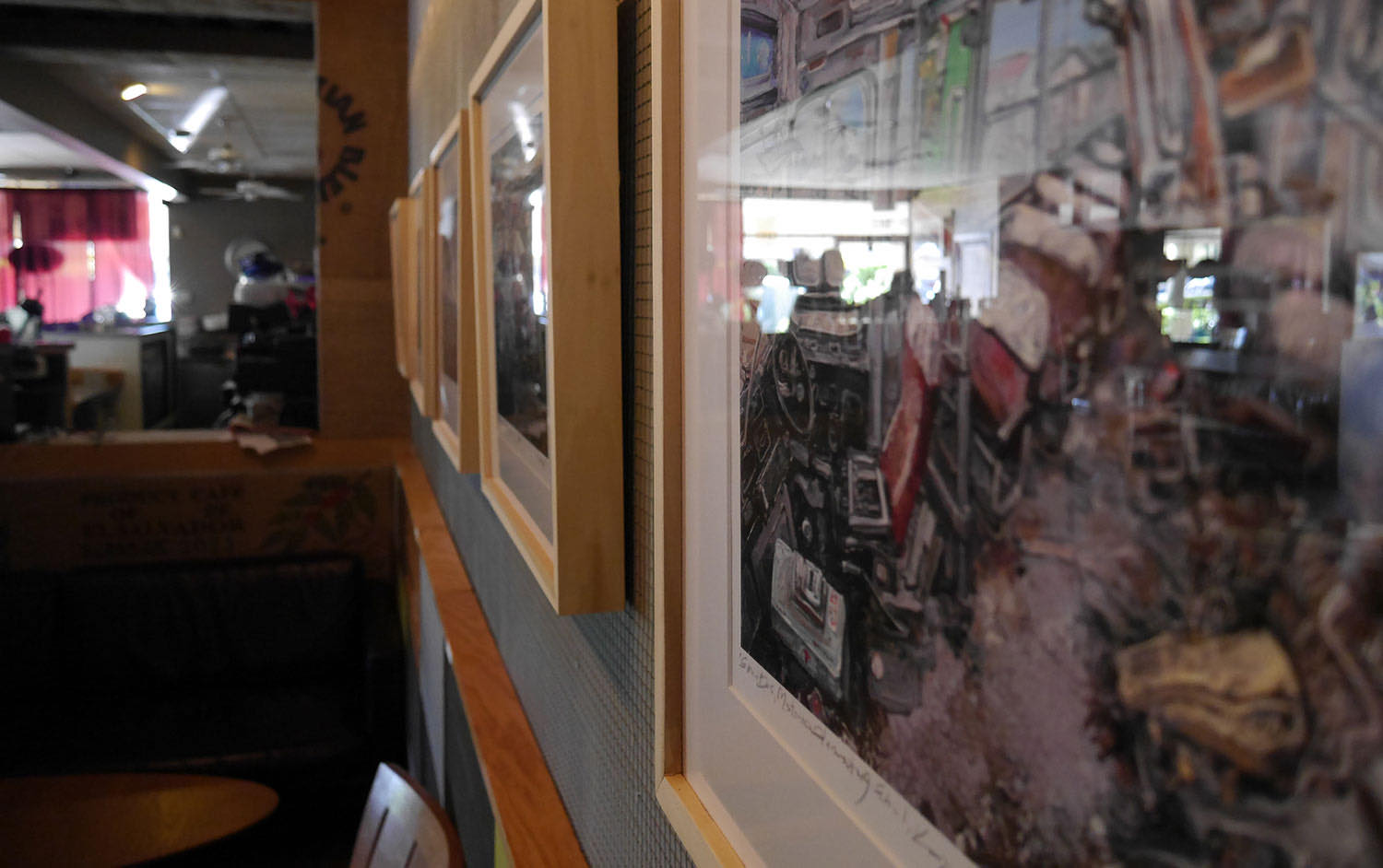 Framed artwork by local artists hanging along the coffee shop wall