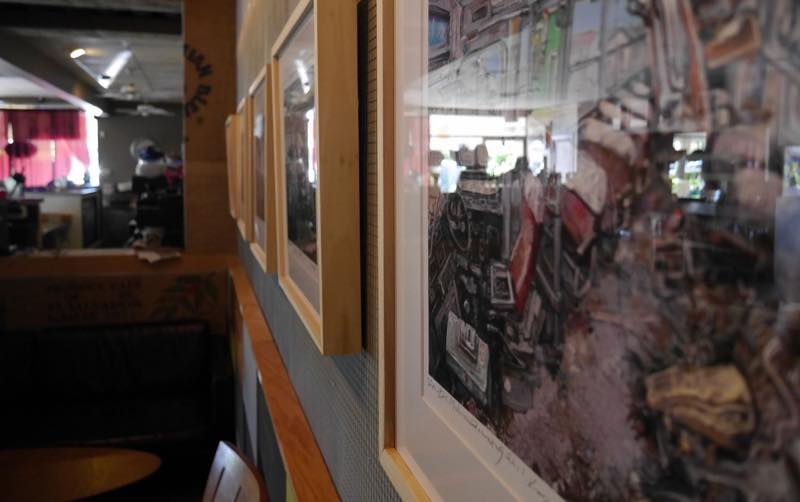 Framed artwork by local artists hanging along the coffee shop wall