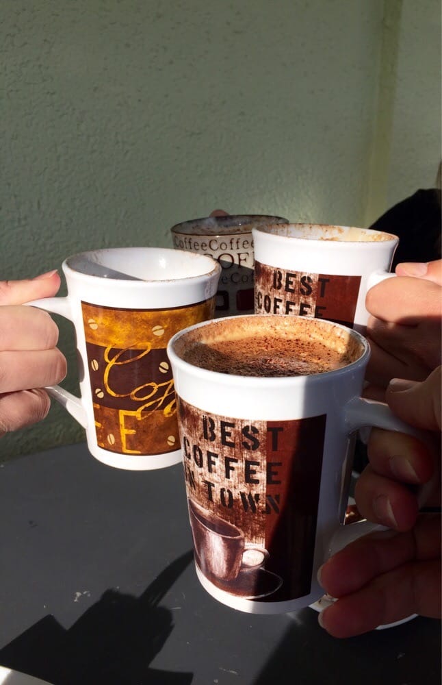 Friends clinking coffee mugs on the sunny patio