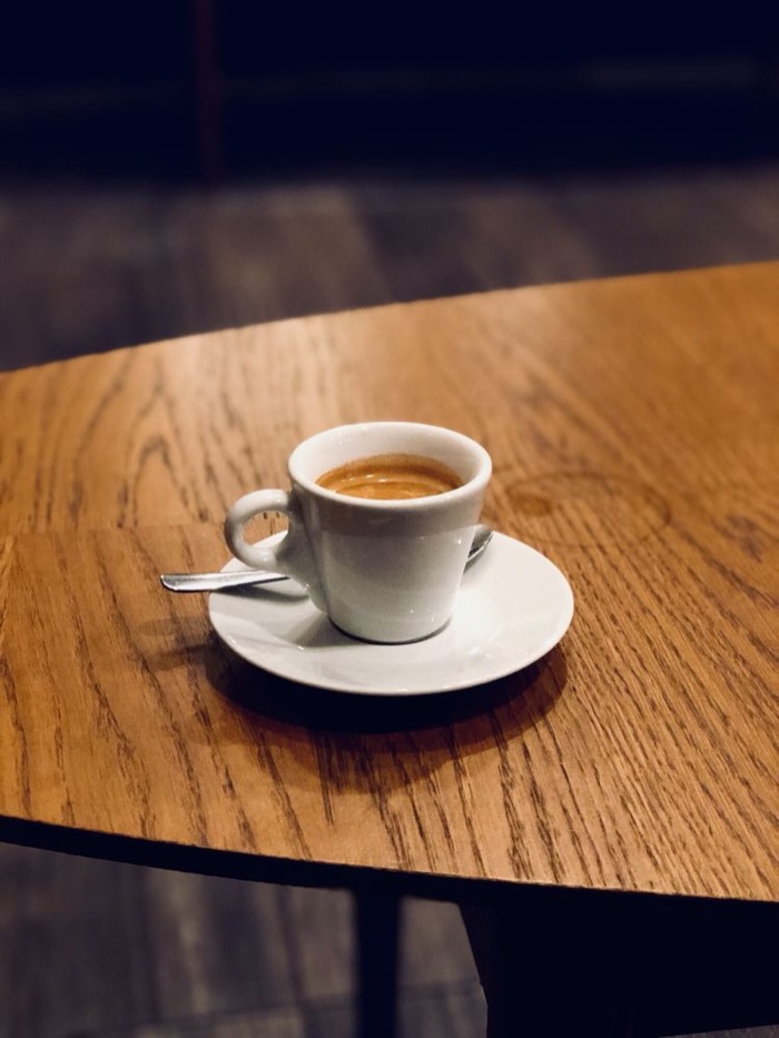 A shot of espresso in a white cup on a wooden table