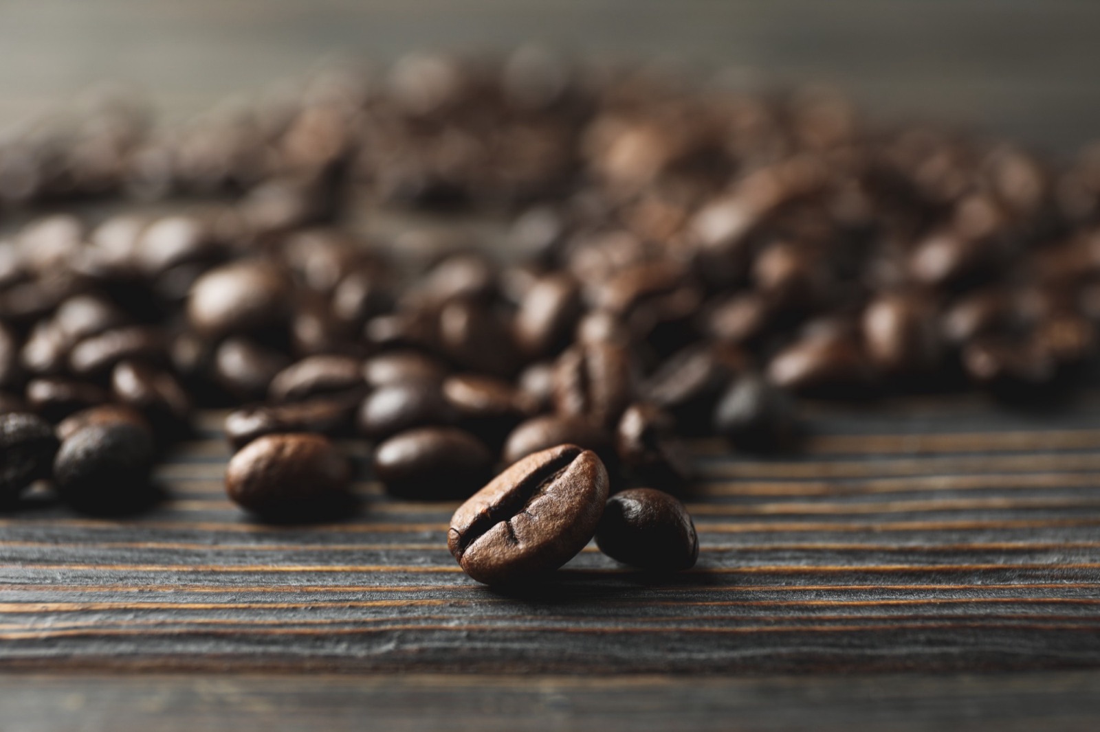 Roasted coffee beans scattered on a dark wooden table